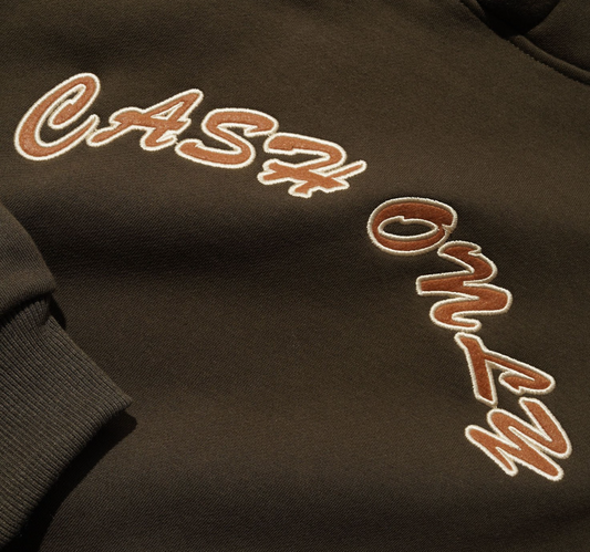 Brown sweatshirt with embroidered text on a dark background