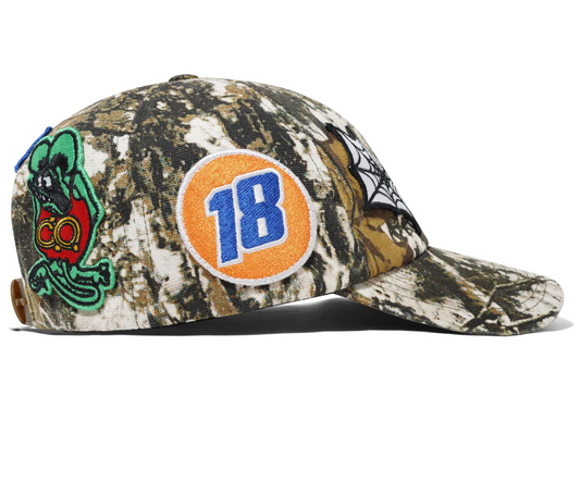Camouflage cap with a colorful patch featuring the number 18 and a logo on a white background
