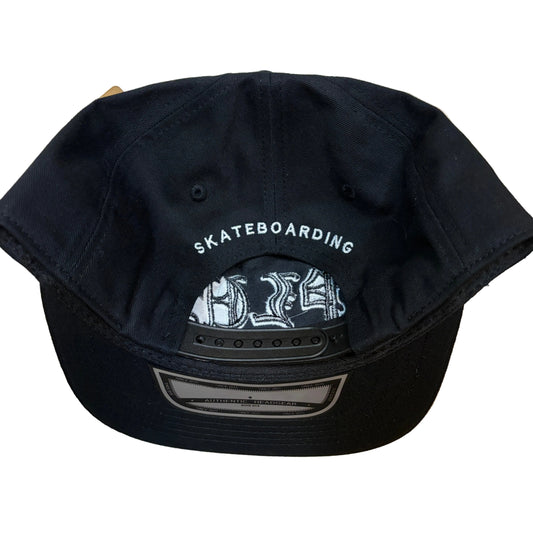 Black cap with 'Skateboarding' text on a wooden surface