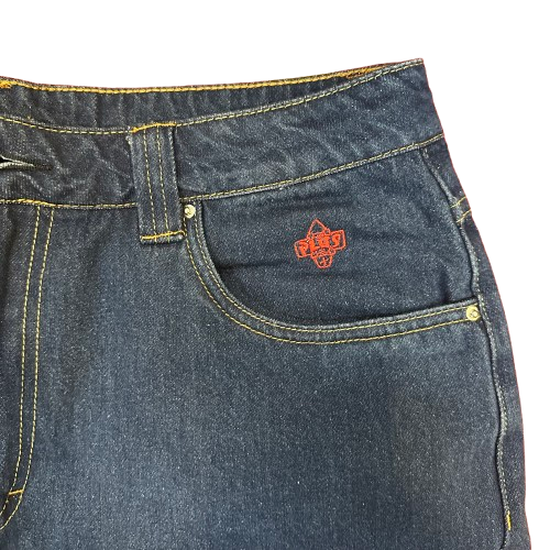 Close-up of dark blue denim jeans showing the front pocket with a red embroidered Plus logo and contrast yellow stitching.