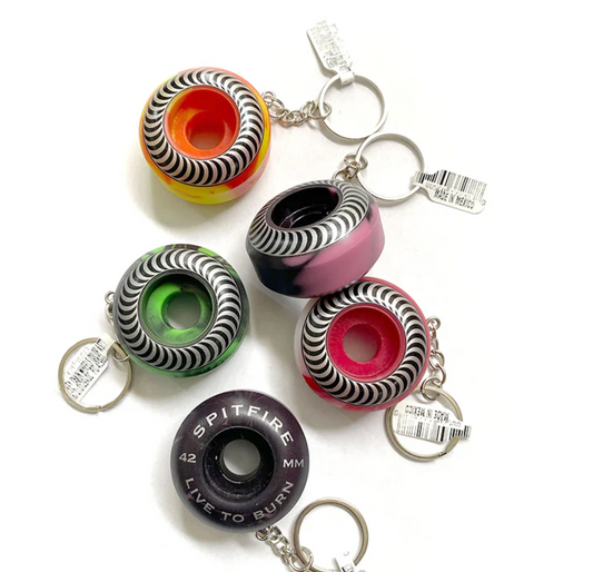 Colorful skateboard wheel keychains with Spitelre branding on a white background