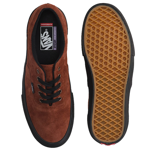 A pair of Vans Pop x Invisibilia low-top sneakers shown from the top and bottom views. The shoe upper is made of brown suede, with black laces, a black rubber sole, and a tan waffle-patterned outsole visible on the right shoe.
