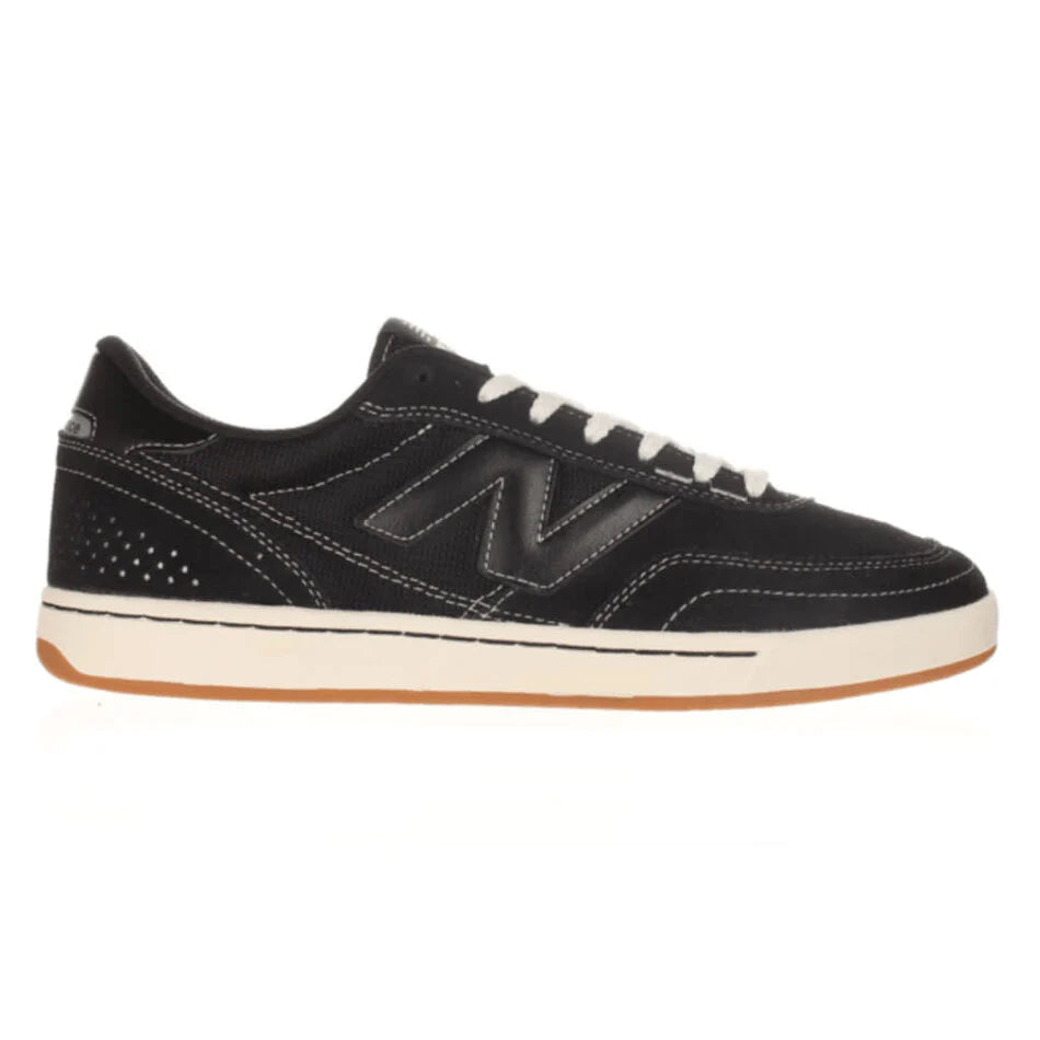 Black sneaker with white laces and brown sole on a white background