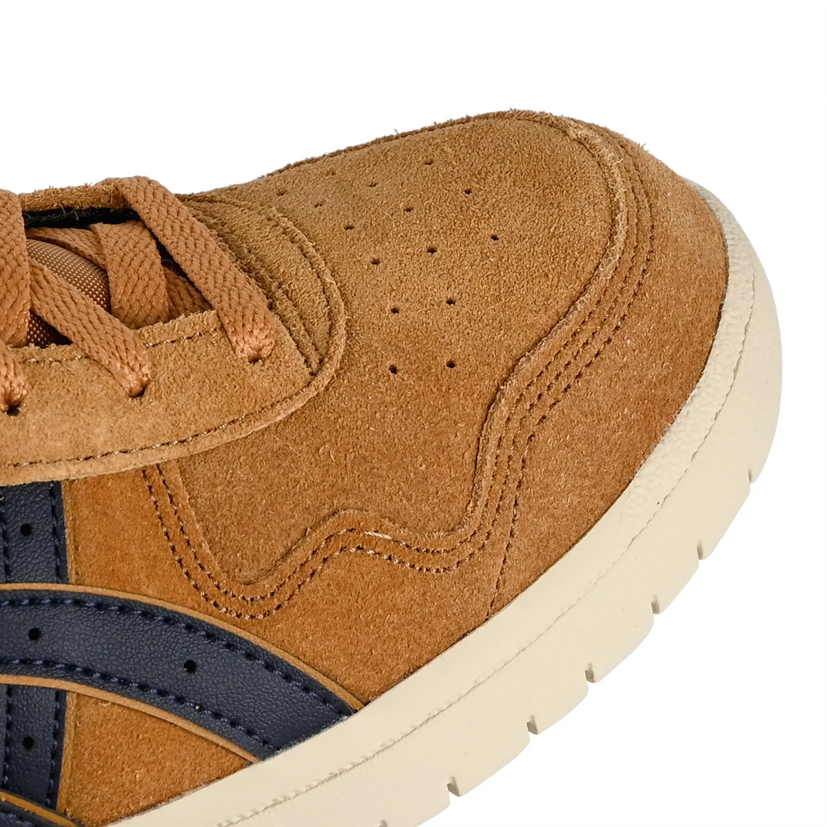 Close-up of a brown suede sneaker showing the toe, laces, side panel, and a cream-colored sole against a white background.