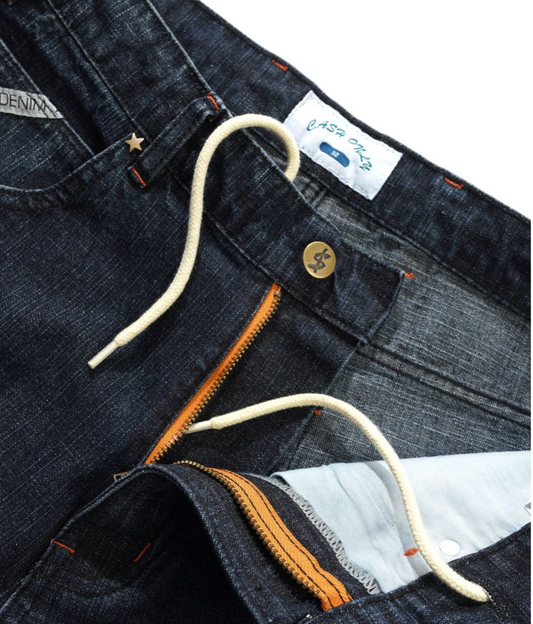 Close-up of dark blue denim jeans with a brand label on a white background