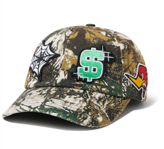 Camouflage baseball cap with various patches including a dollar sign, spider web, and others on a white background.