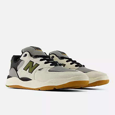 New Balance sneakers in off-white, gray, and black with a green 'N' logo and a gum sole