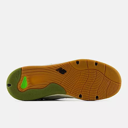 The outsole of a New Balance sneaker, showing a brown gum rubber tread with a green heel section and a small bright green logo accent.