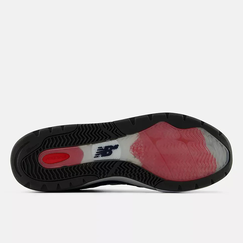 The outsole of a New Balance sneaker, showing a black treaded edge with a translucent pink and red cushioned area and a white New Balance logo.