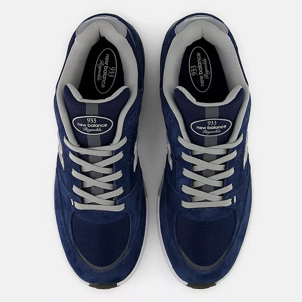 A pair of New Balance 933 sneakers shown from a top-down view. The shoes feature a navy blue suede and mesh upper with light gray laces, gray inner lining, and a white midsole.