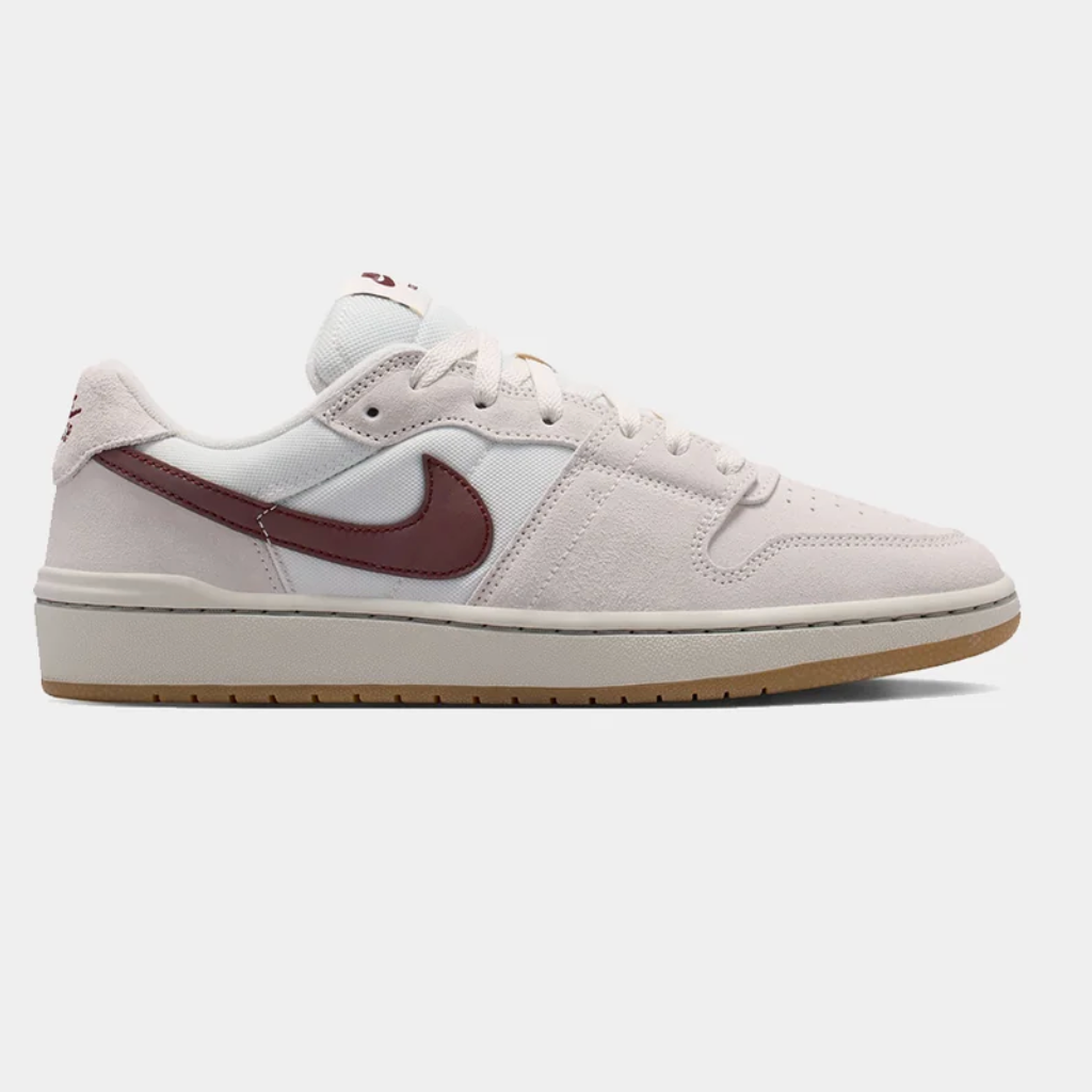 A Nike sneaker in a light off-white and beige colorway, featuring a burgundy Swoosh on the side, a white tongue, and a gum outsole, shown against a light gray background.