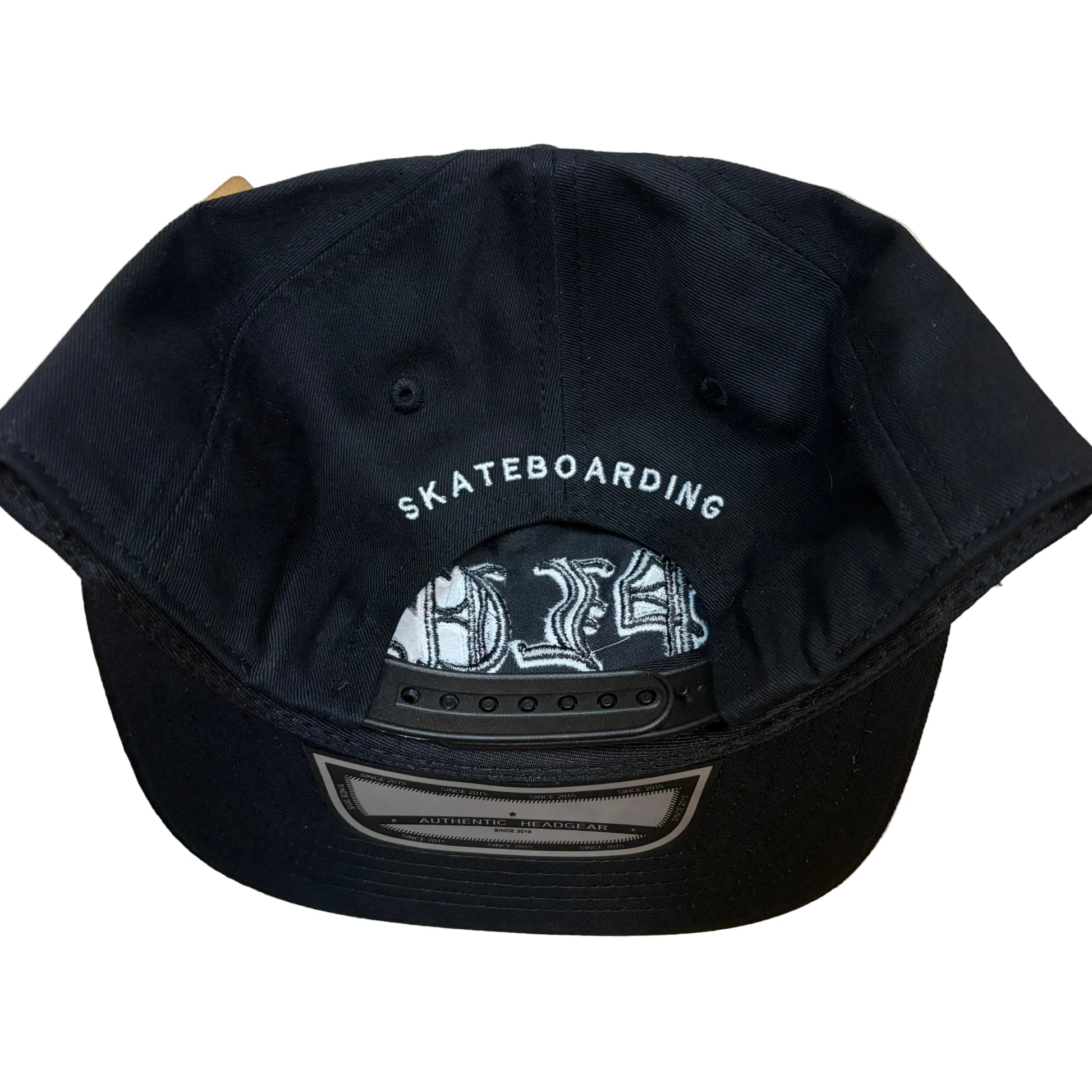 Black cap with 'Skateboarding' text on a wooden surface