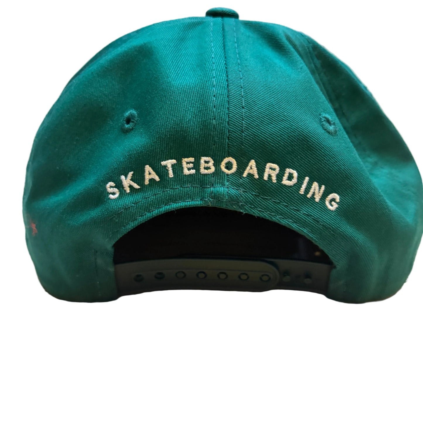 Green cap with 'SKATEBOARDING' text on a wooden surface
