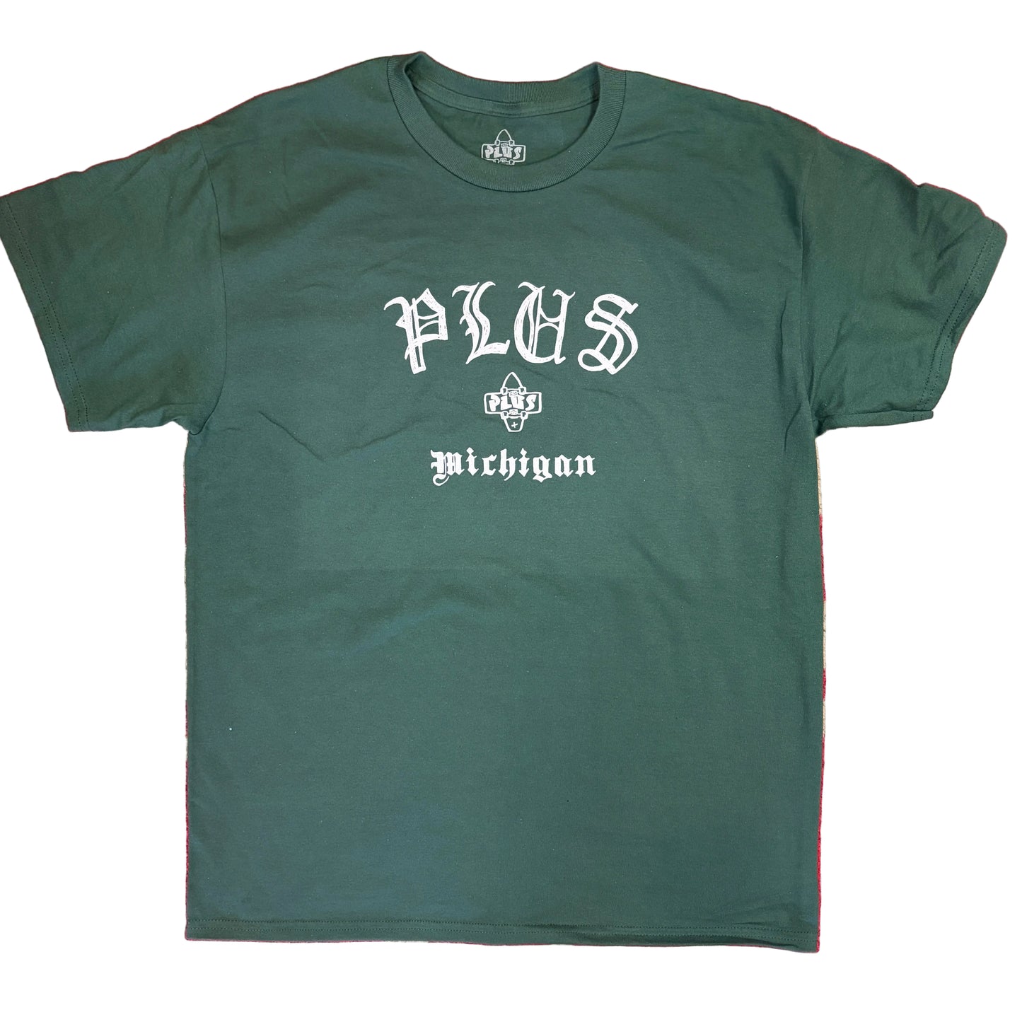 Green t-shirt with 'PLUS Michigan' text on a red and beige patterned background