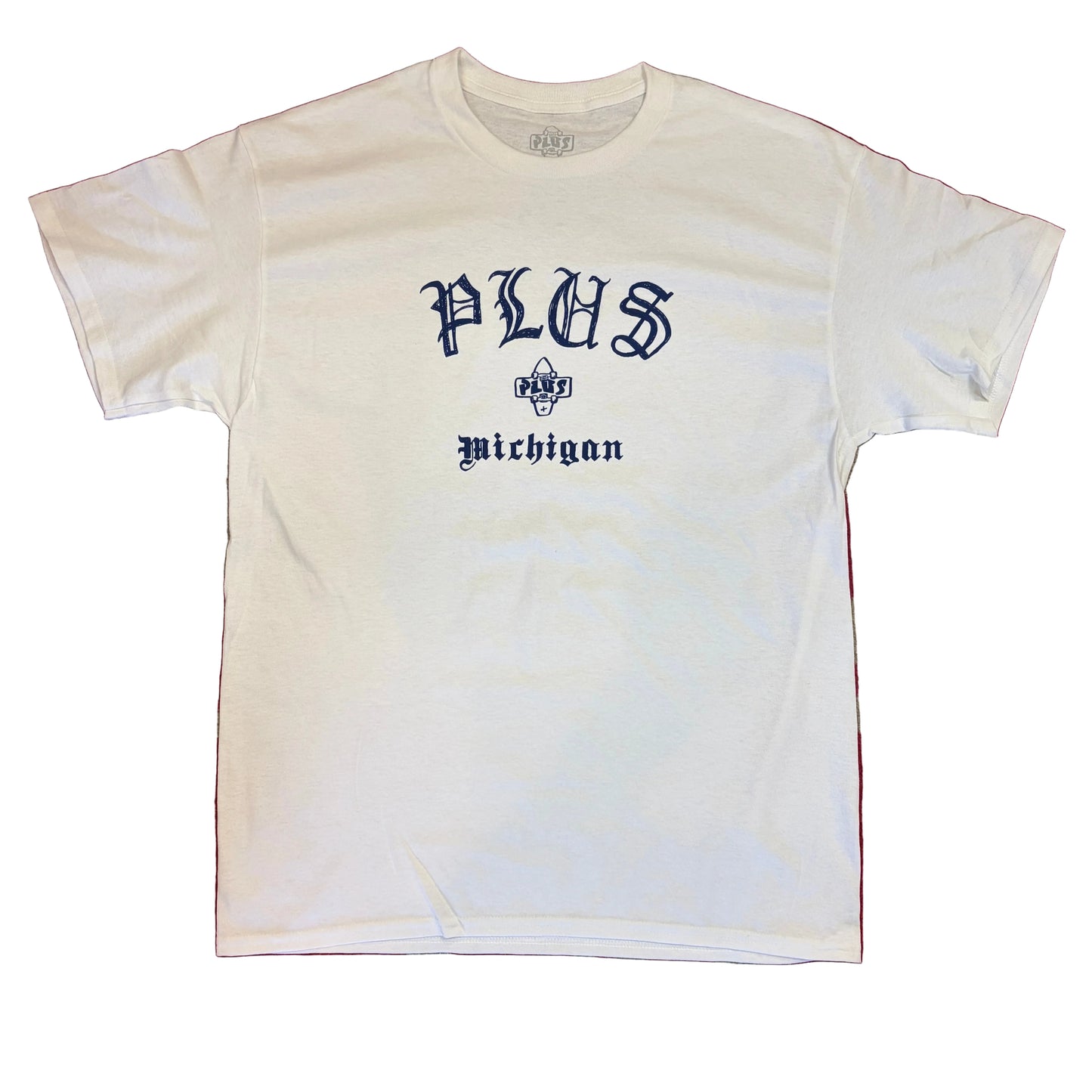 White t-shirt with 'PLUS Michigan' text on a red and beige patterned surface