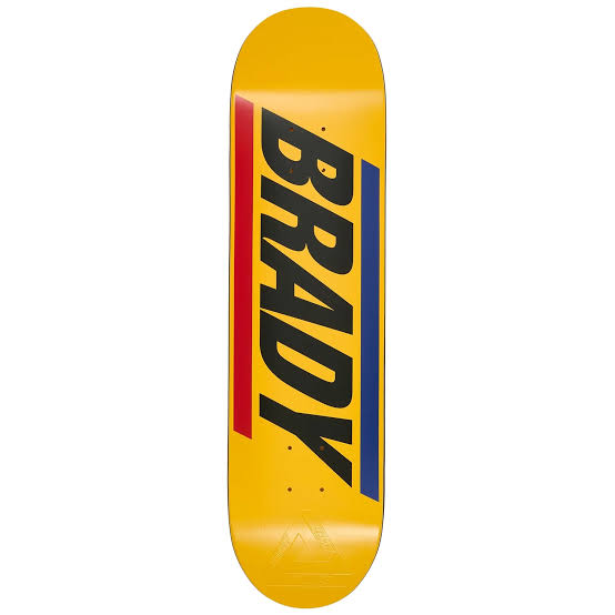 A yellow skateboard deck featuring the name 'BRADY' in large black letters, flanked by red and blue vertical stripes, shown against a plain white background.