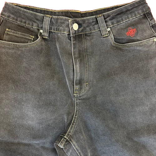 Close-up of a pair of black denim jeans showing the waistband, belt loops, button, front pockets, and a red embroidered 'PLUS' logo on the right pocket.