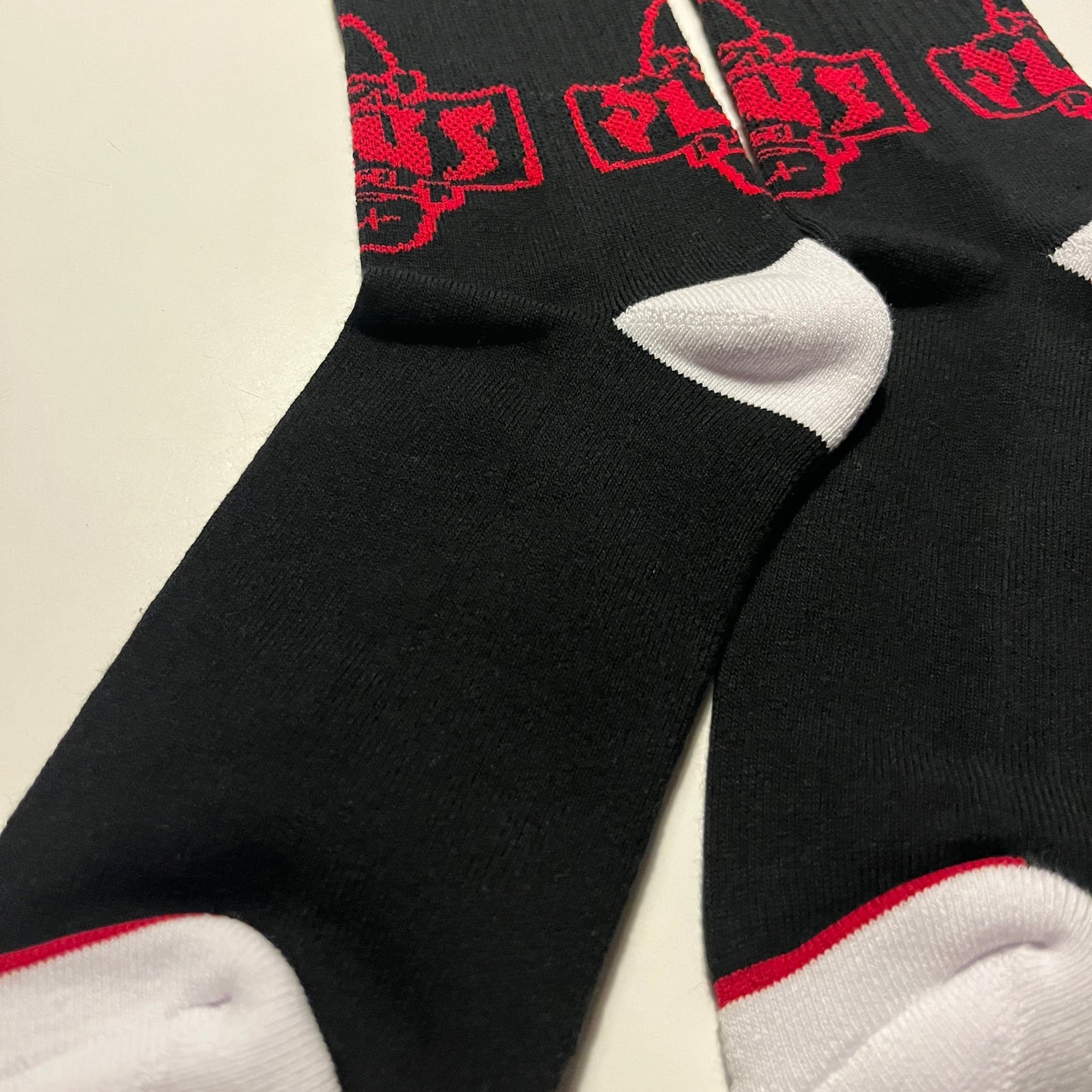 Black socks with red patterns and white toes and heels on a beige background
