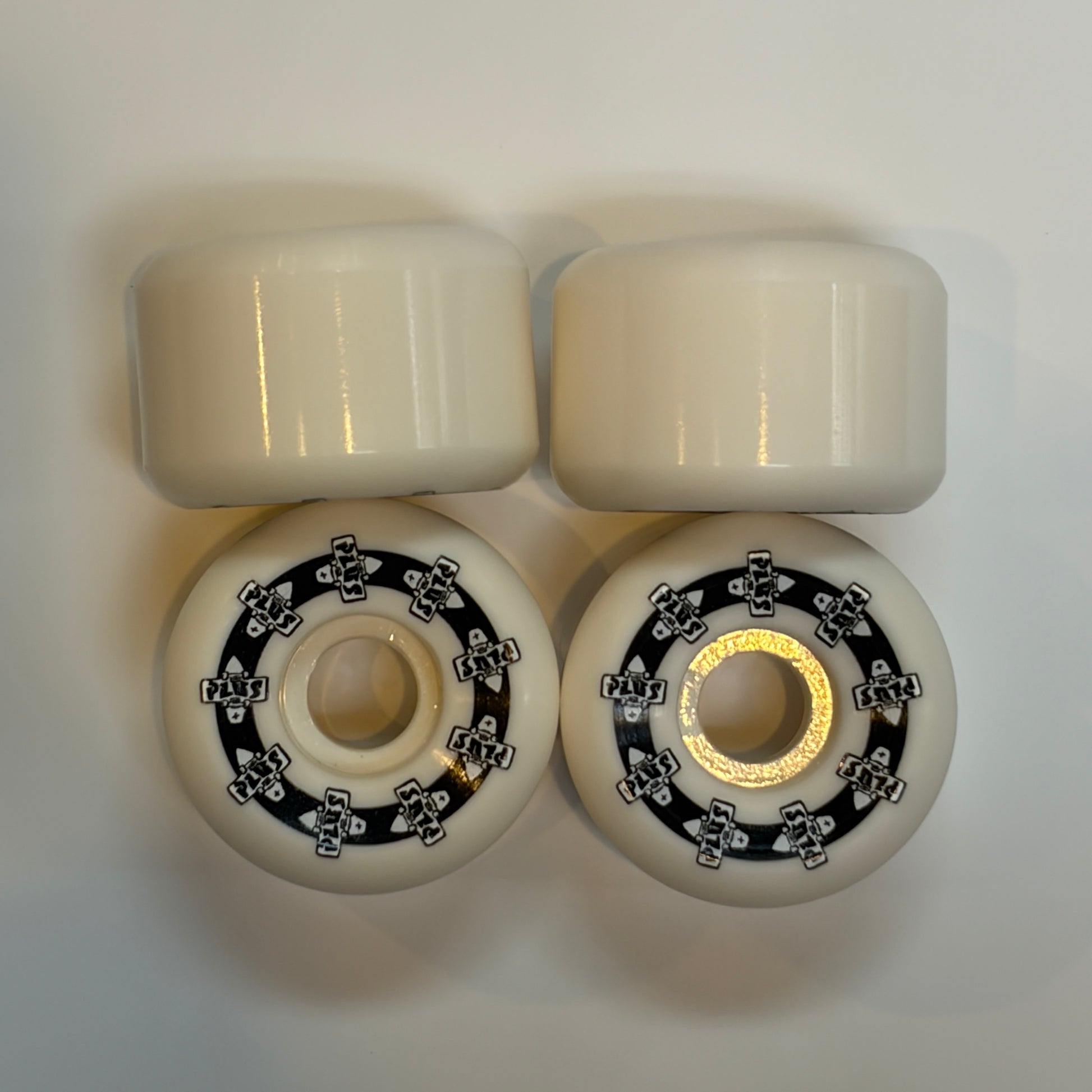 Four white skateboard wheels with metal bearings on a light gray background
