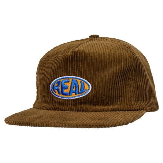 A brown corduroy flat-brim cap featuring an embroidered oval logo on the front with the word 'REAL' in blue and orange.