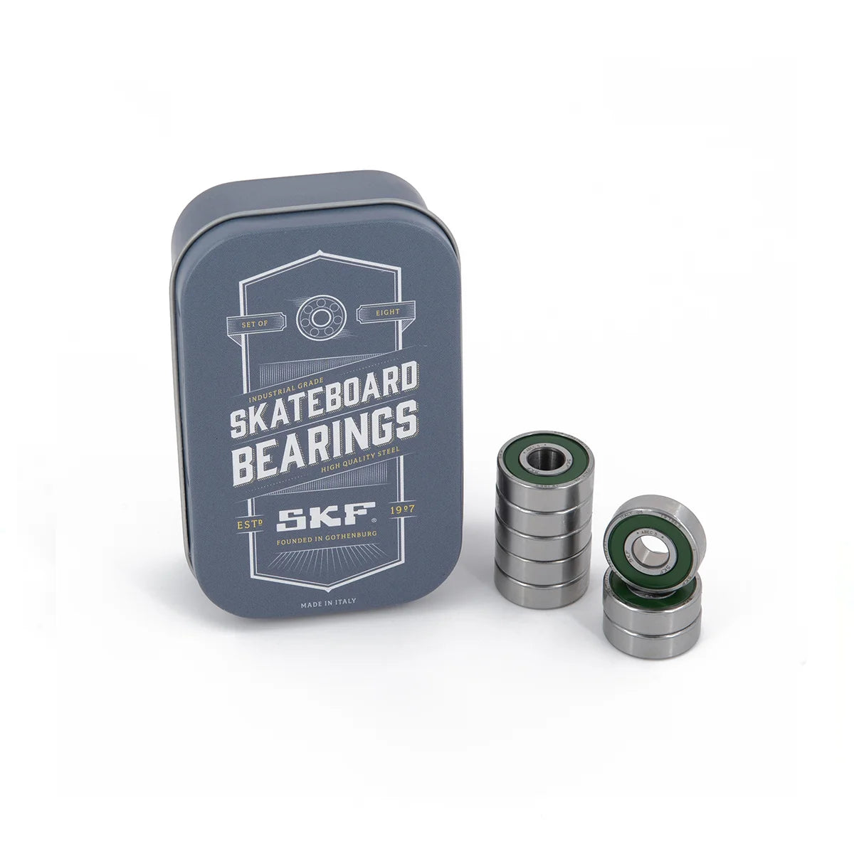 A dark gray metal tin labeled 'SKATEBOARD BEARINGS' and 'SKF' stands next to three stacked skateboard bearings with green inner rings on a clean white background.