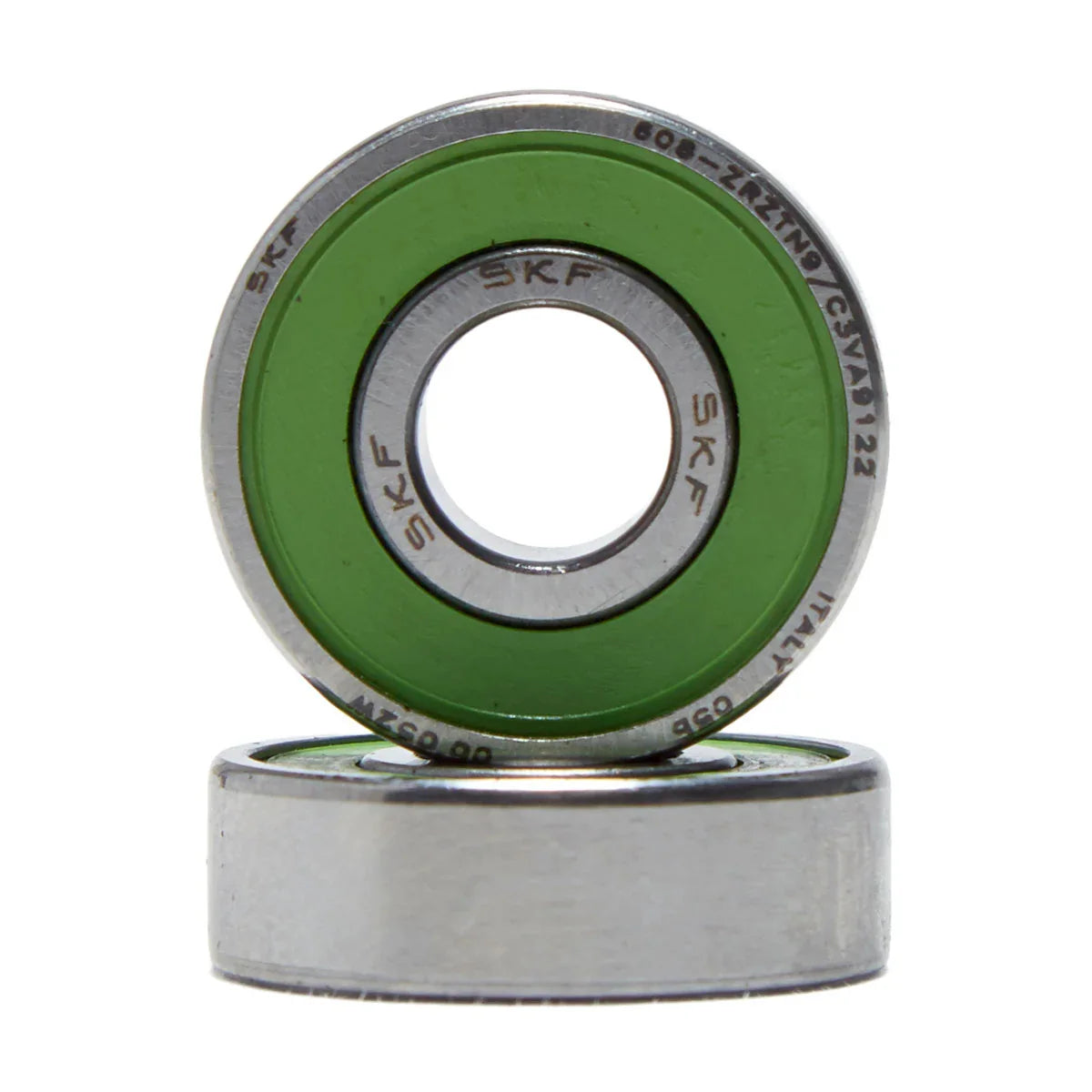 Two SKF ball bearings stacked on a white background, with one bearing upright showing its green inner ring and silver metal outer ring, and the other lying flat below it.