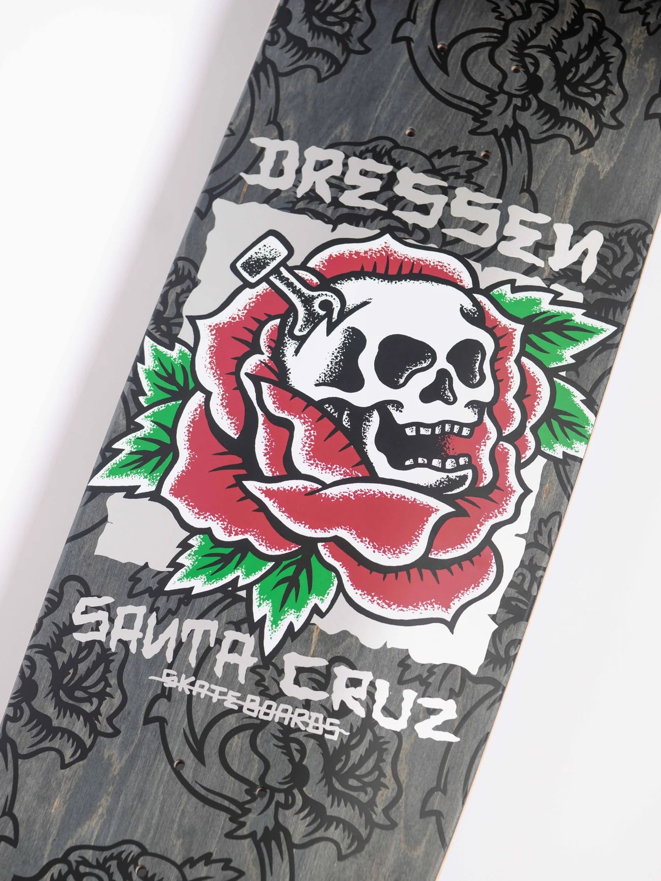 Skateboard deck with skull and rose design and 'Santa Cruz' branding.