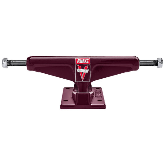 A pair of dark maroon skateboard trucks with silver metal axles and nuts, featuring a red and white 'AWAKE' brand logo on the deck plate