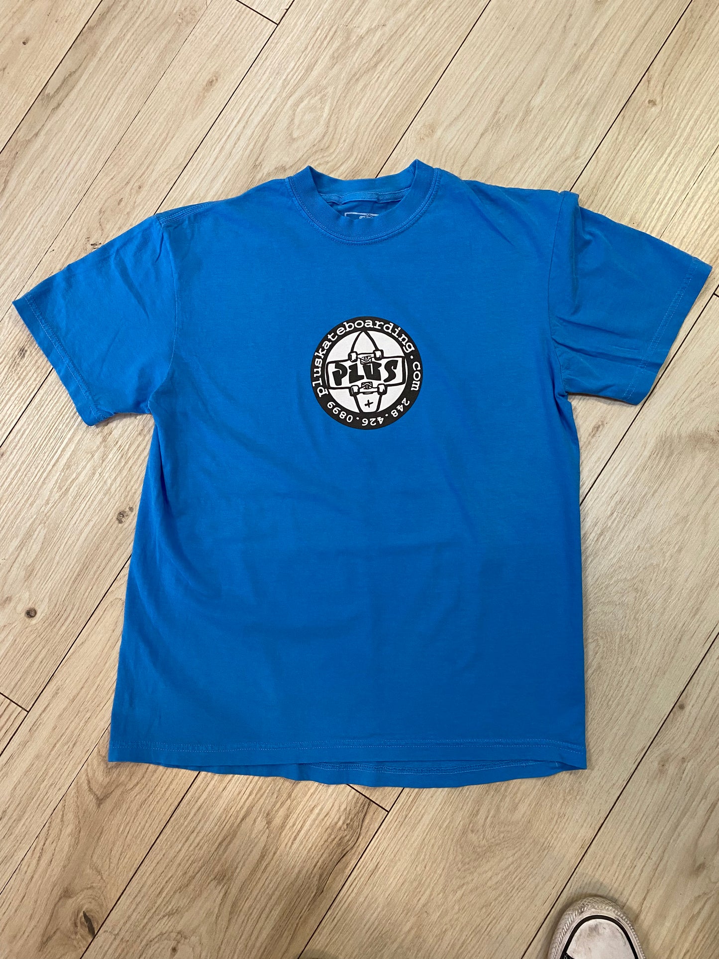 Blue t-shirt with a logo on a wooden floor